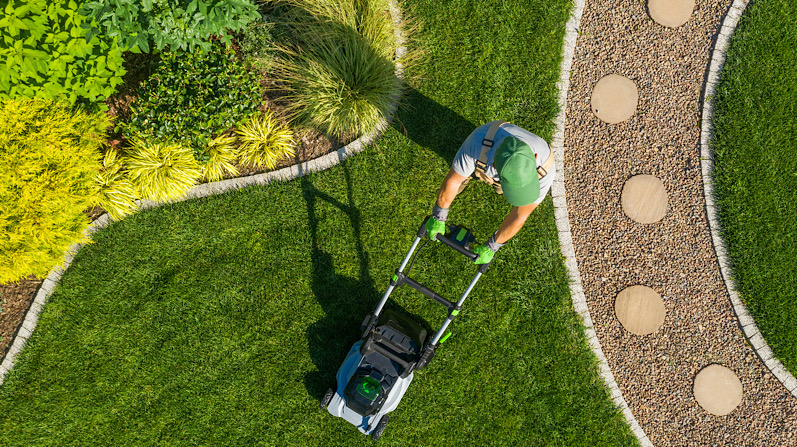 Gardener Mowing Backyard Garden Grass Aerial View. Lawn maintenance/stoke on trent